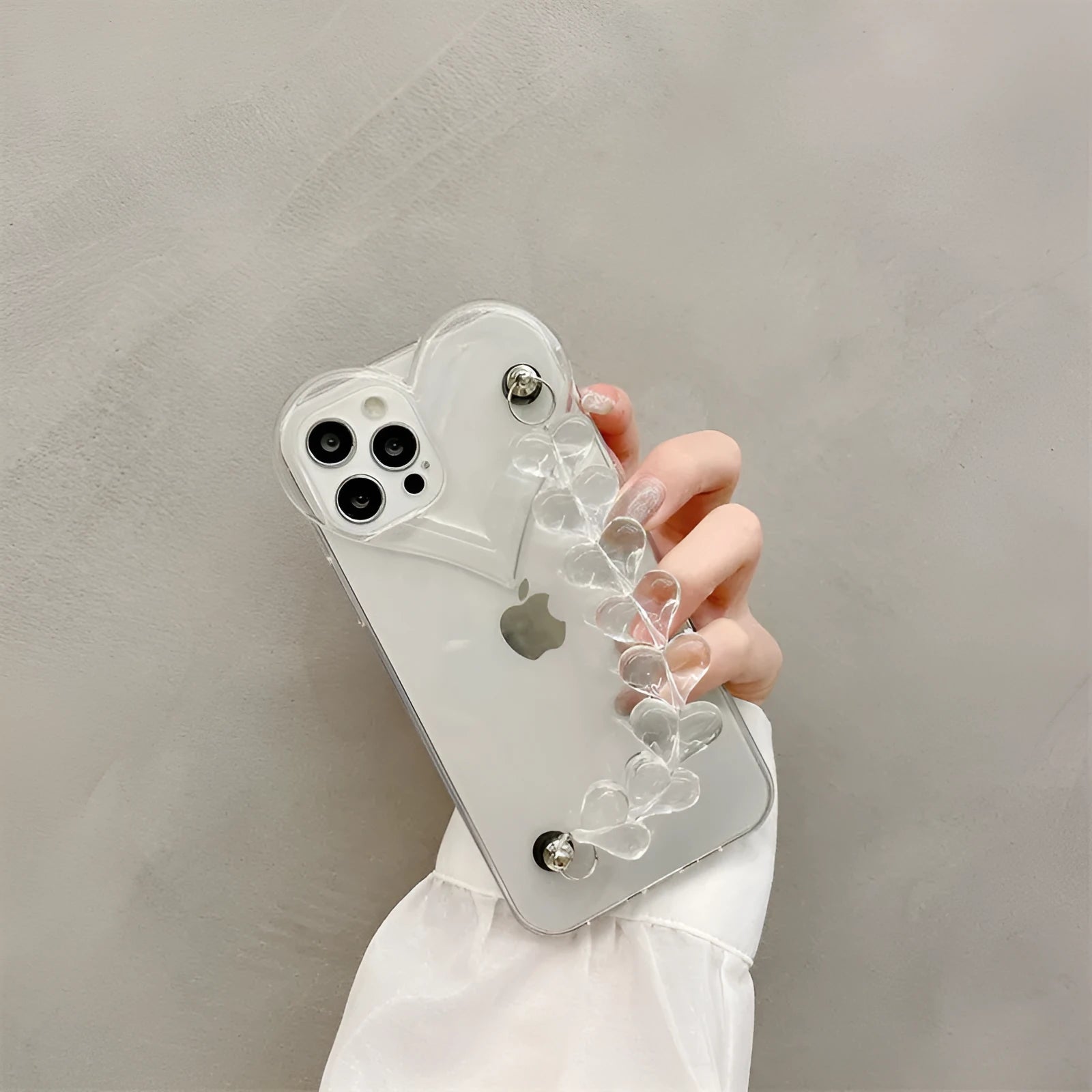 Transparent iPhone case with a love heart charm on a chain, on an iPhone.