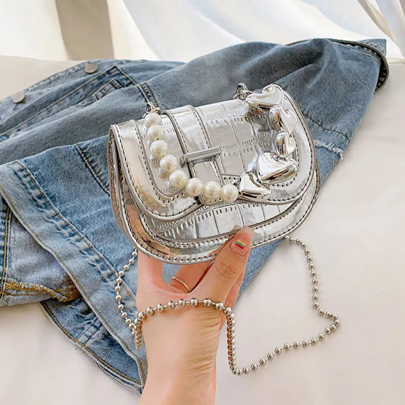 Laser pearl finish mini tote saddle crossbody bag in a choice of colours, shown with a single strap and structured square shape.