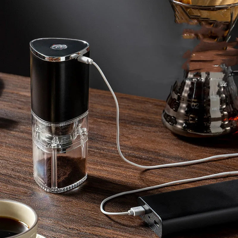 White portable electric coffee grinder with USB charging cable on a wooden table