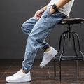 Man wearing loose straight leg cargo jeans in blue, showing mid waist and zipper fly detail.