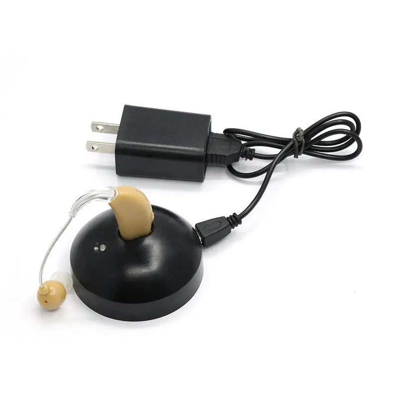 Black silicone rechargeable hearing aid amplifier for elderly users on a charging cable.