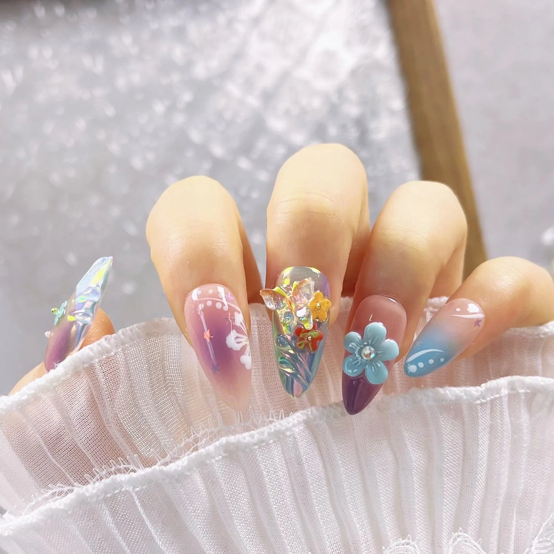 Handmade press-on false nails with embossed colourful small flowers and butterfly designs in almond shape.