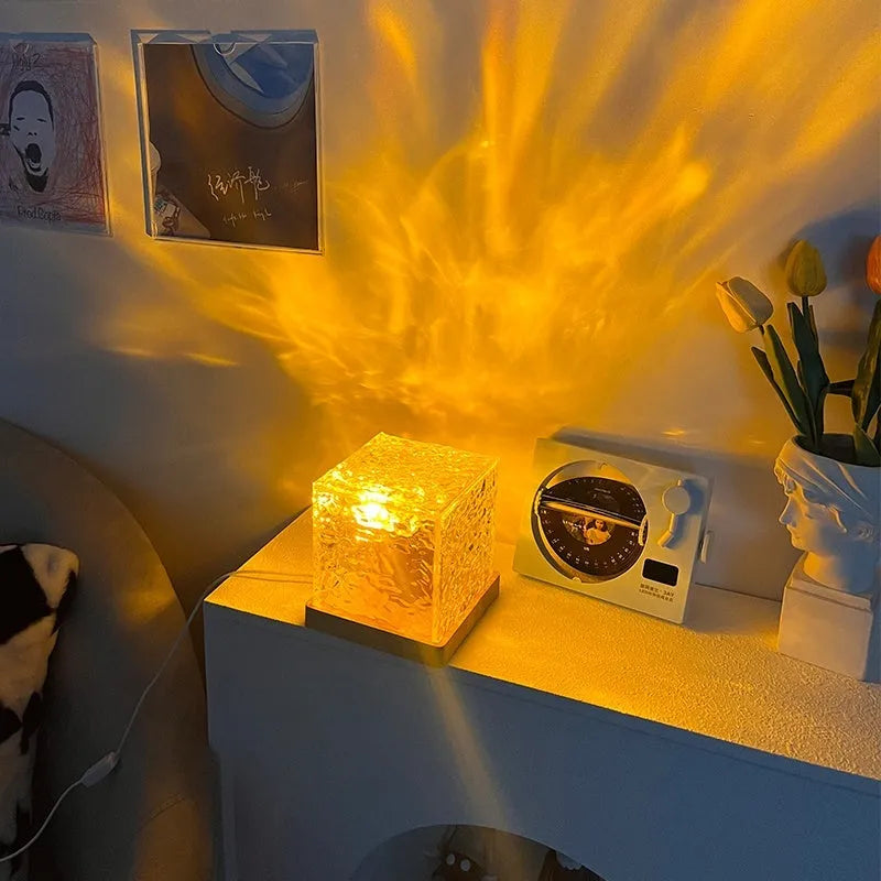 Crystal table lamp projecting blue water ripple light effect onto a wall, with remote control.