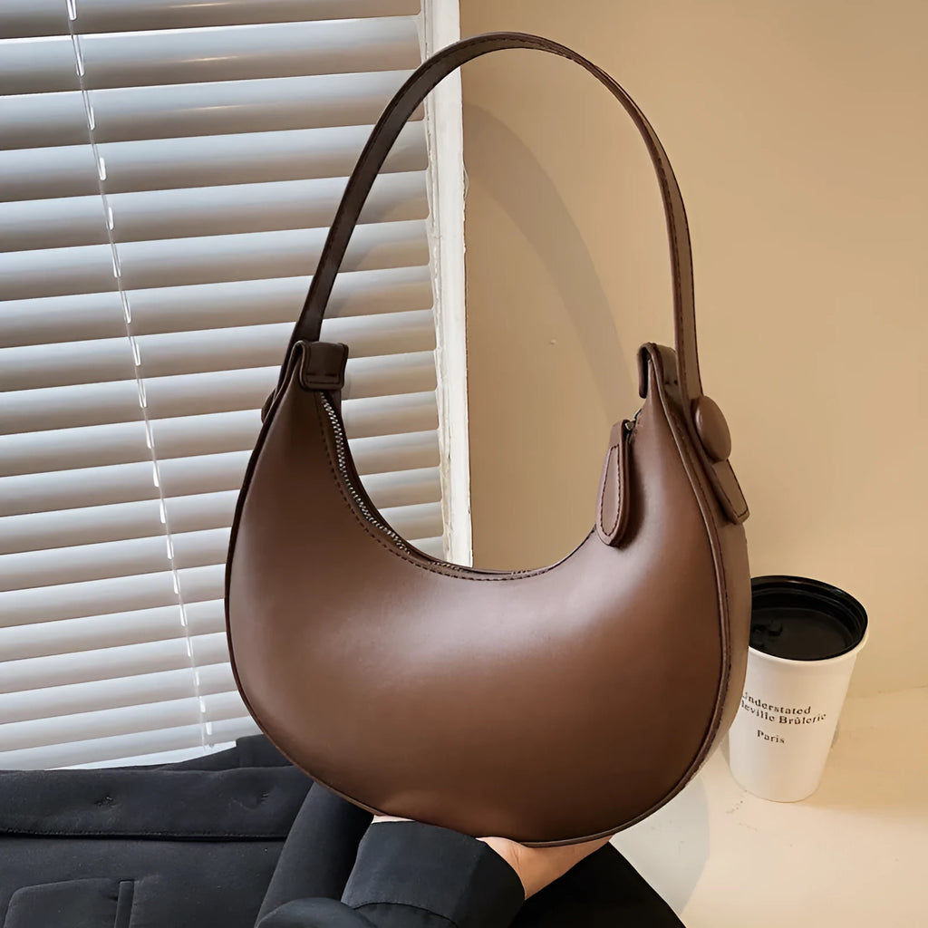 Women's retro-style PU dumpling shoulder bag in black, showing front zipper compartment.