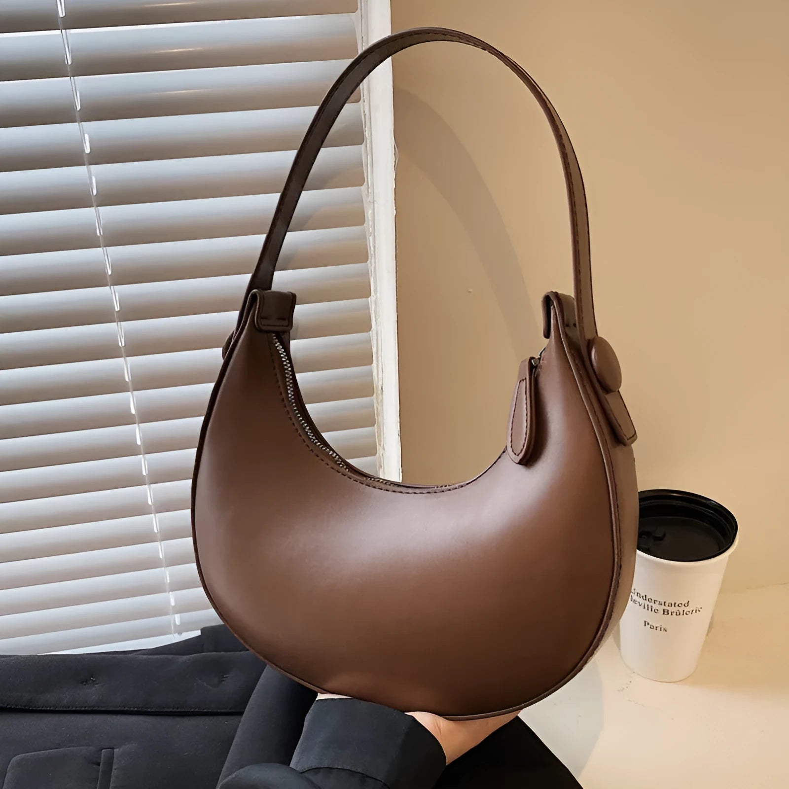 Women's retro-style PU dumpling shoulder bag in black, showing front zipper compartment.