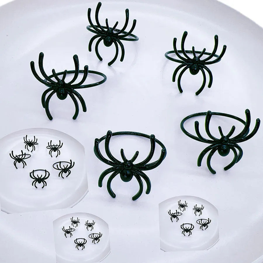 Set of six black metal spider-shaped napkin rings for Halloween table decoration.