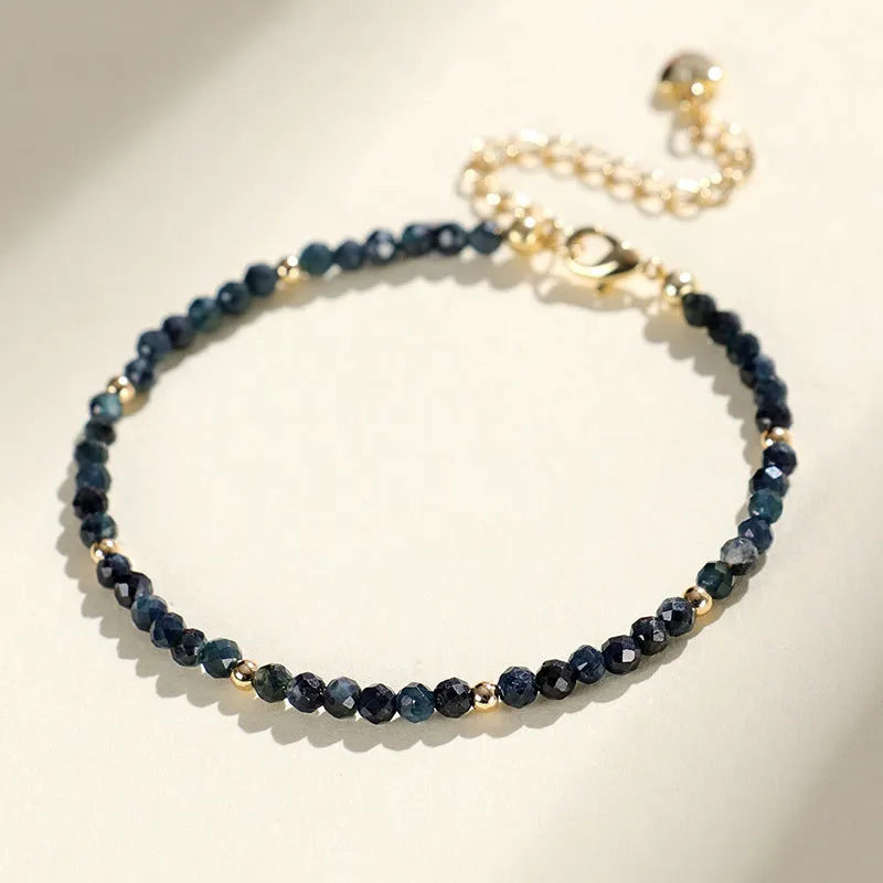 Blue tourmaline gemstone bracelet with 3mm beads and gold spacer details.