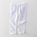 Men's straight-leg linen trousers in light grey, laid flat to show the mid-waist and tailored cut.