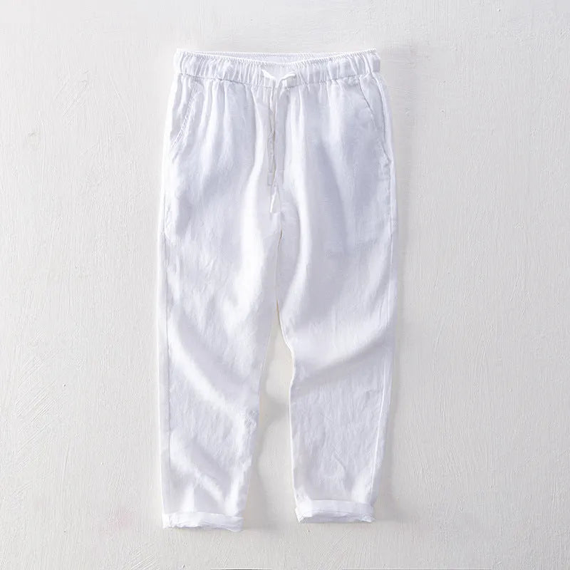Men's straight-leg linen trousers in light grey, laid flat to show the mid-waist and tailored cut.
