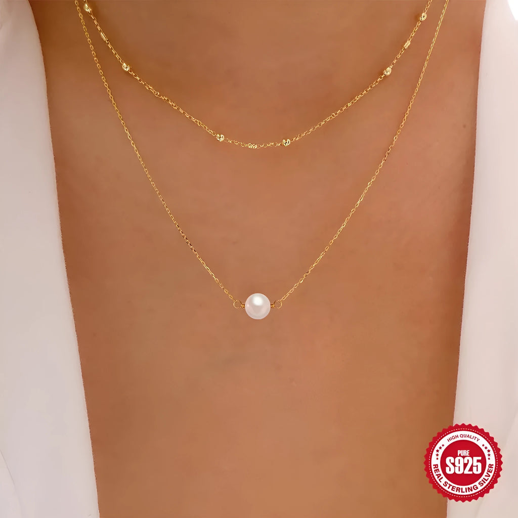 Close-up of a women's double layer sterling silver necklace with two round freshwater pearls on a geometric pendant.