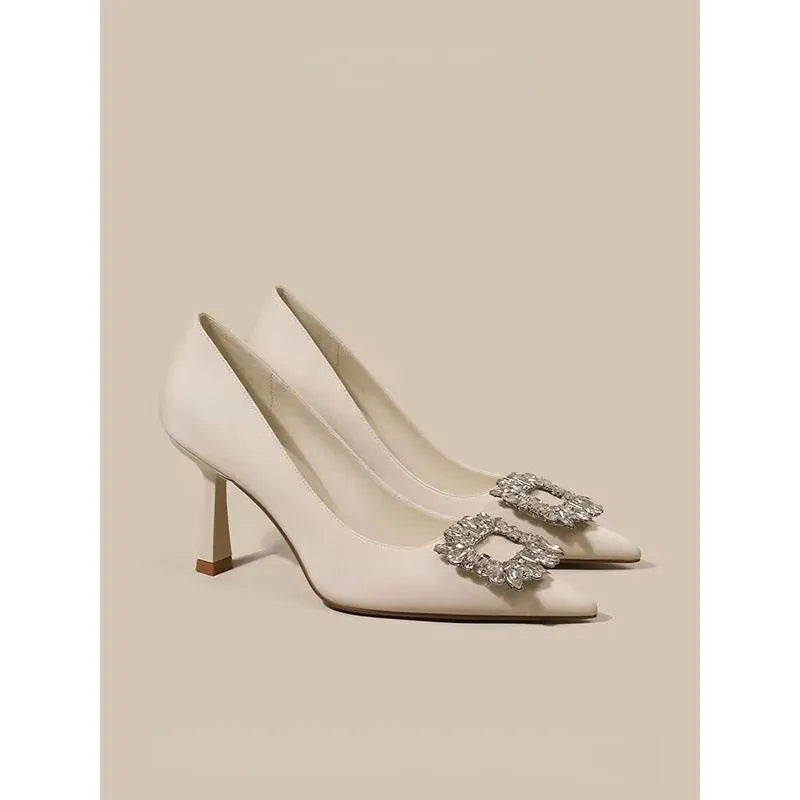 Women's creamy-white pointed toe stiletto pumps with a mid-height heel on a plain background.