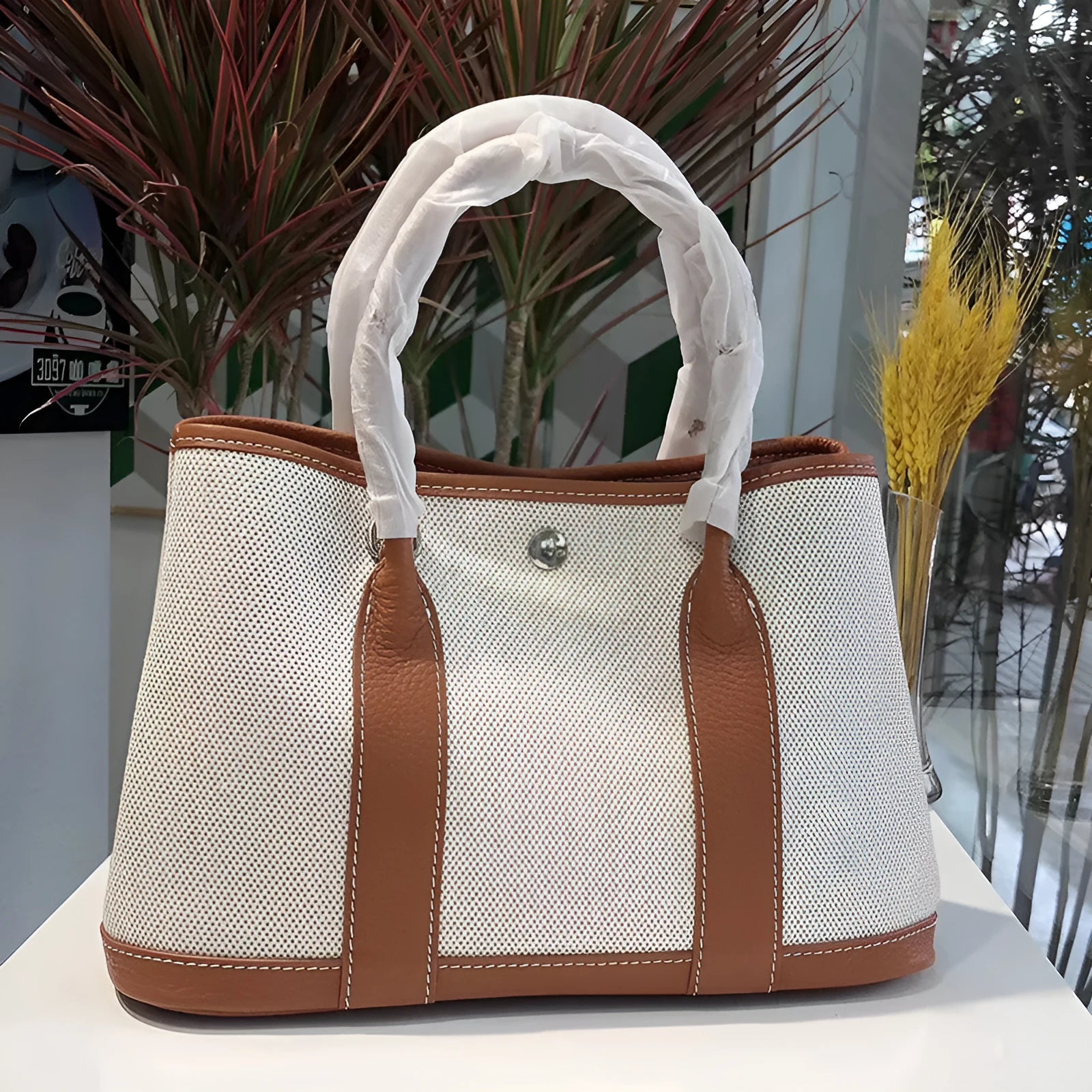Women's canvas bucket tote bag with genuine leather trim, shown with crossbody strap and carry handle