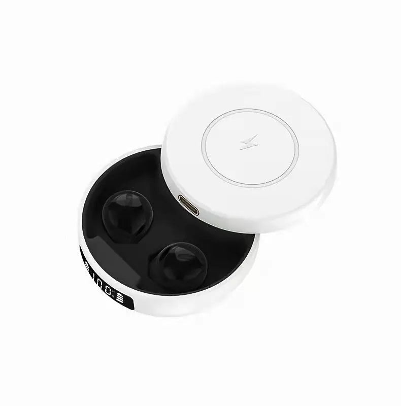 Mini black and white semi-in-ear wireless headphones with their wireless charging case on a table.