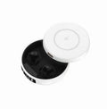 Mini black and white semi-in-ear wireless headphones with their wireless charging case on a table.