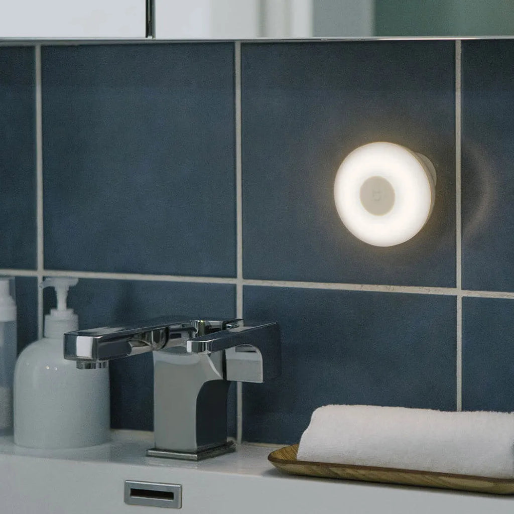 White modern bedside table lamp with sensor and Bluetooth on a wooden nightstand.