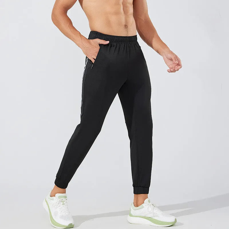 Men's black polyester running trousers with a mid waist fit on a size chart.