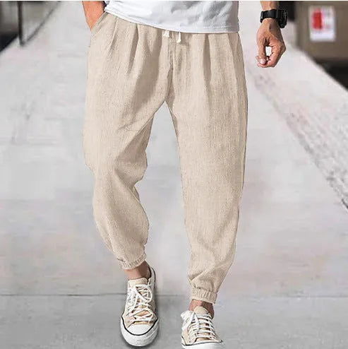 Man wearing loose light-coloured cotton trousers with elasticated ankle cuffs, showing front and side views.