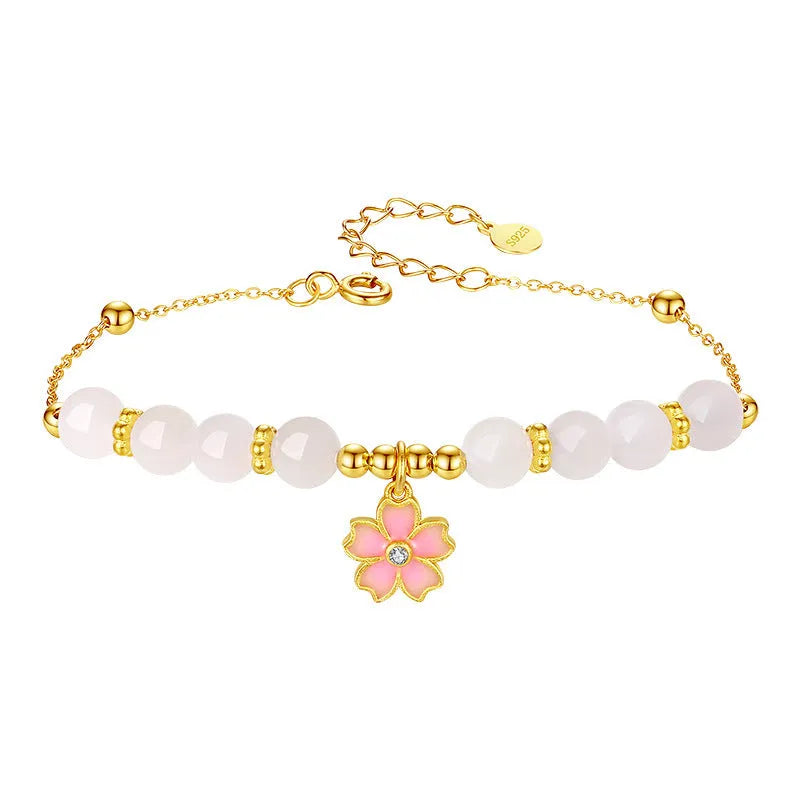 Close-up of a women's pink cherry blossom pendant and Hetian jade bead bracelet made from S925 silver.