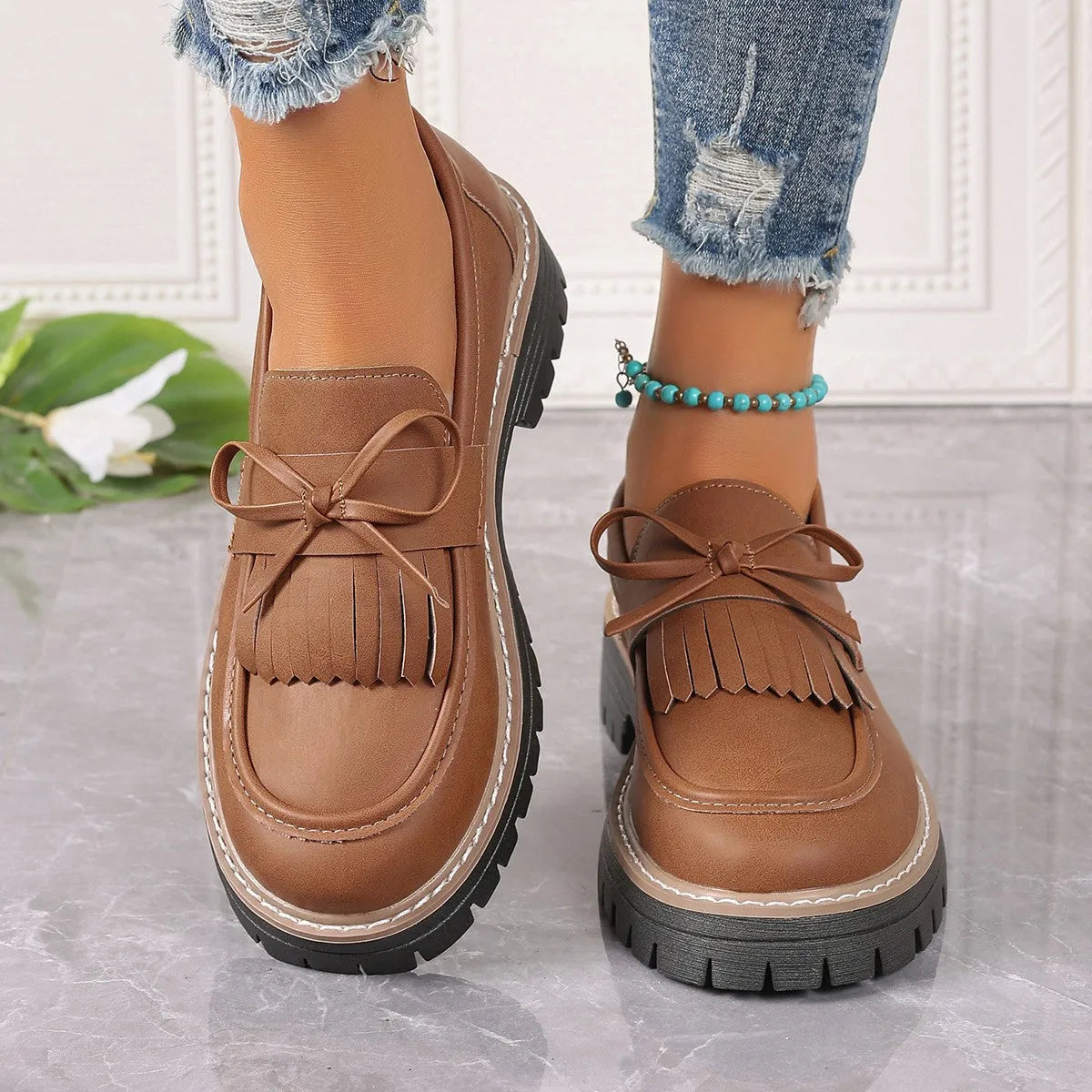 Black women's loafers with a tassel and bow knot on a chunky rubber sole.