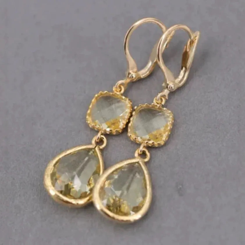 Gold geometric fringe earrings with crystal water droplet details on white background