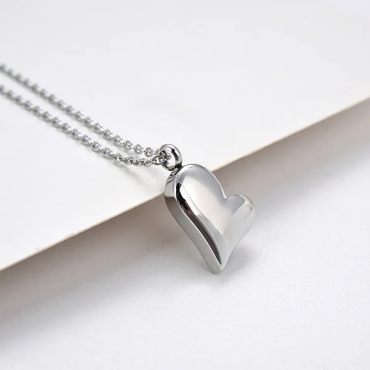 Silver stainless steel necklace with curved peach heart pendant on adjustable chain