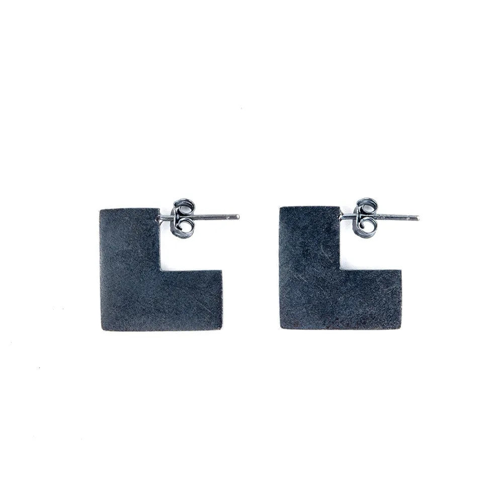 Close-up of a pair of oxidation black geometric square stud earrings made from 925 sterling silver.