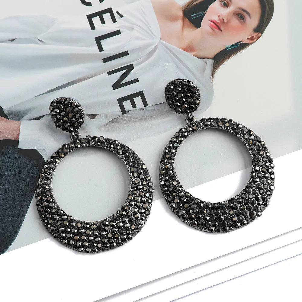 A pair of large round cartoon-style pendant earrings with coloured rhinestones on alloy metal.