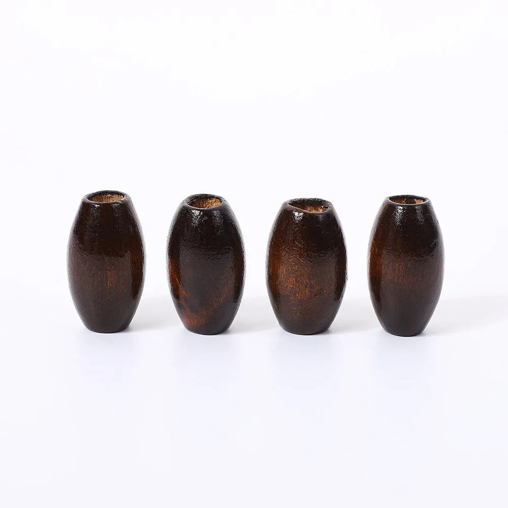 Dark coffee coloured oval wooden bead with a raised M-shaped design, showing scale.