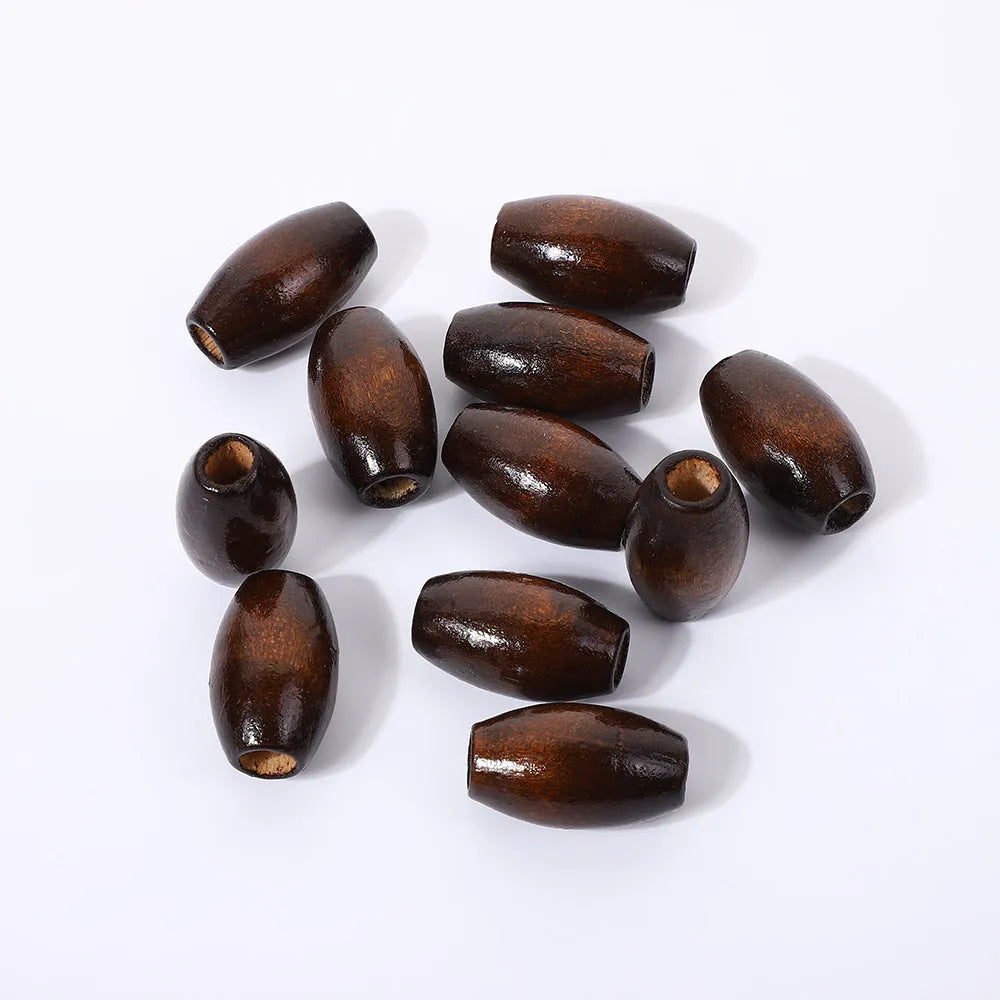 Dark coffee coloured oval wooden bead with a raised M-shaped design, showing scale.