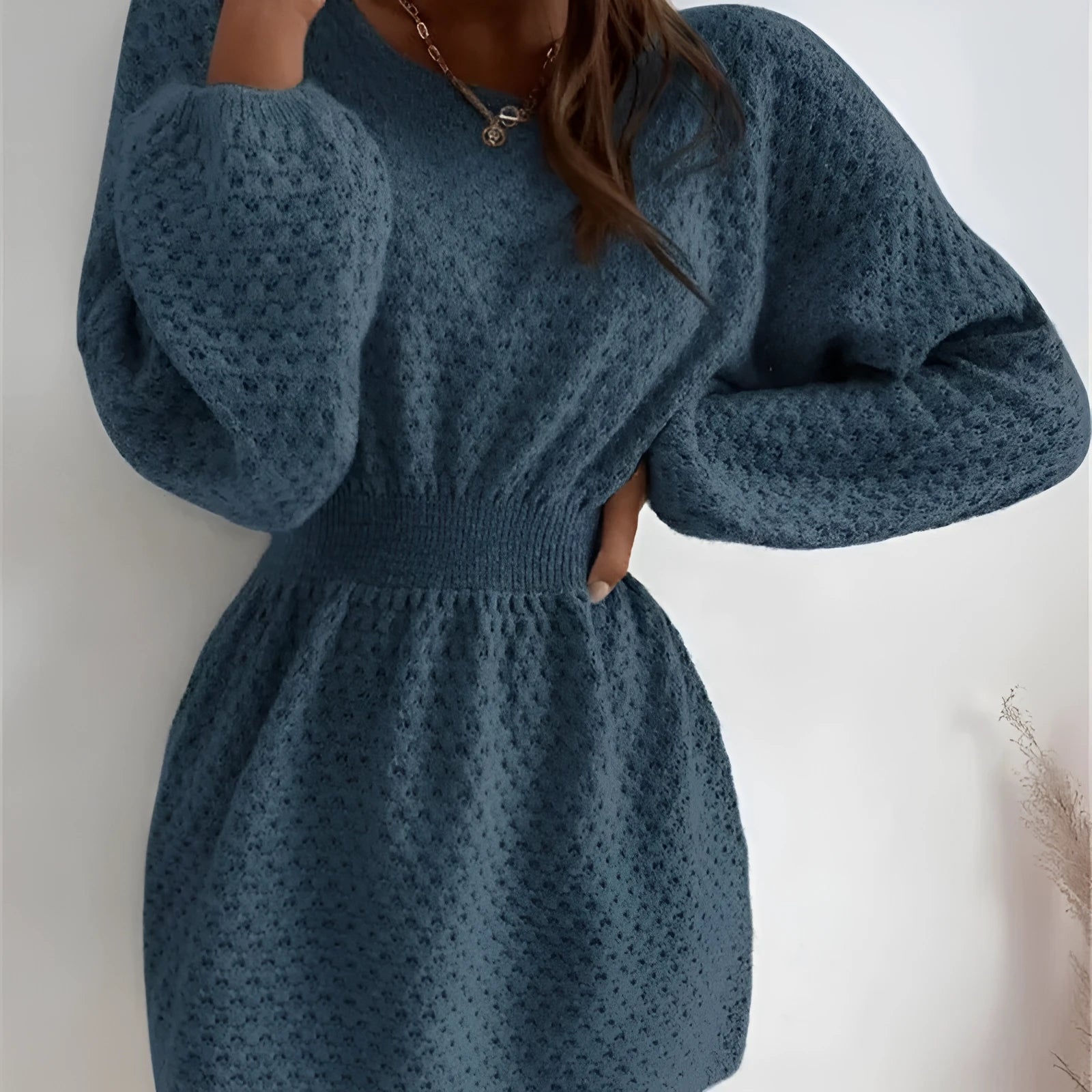 Blue women's knitted dress with white hand-crocheted flower details on the chest, showing a fitted waist and round neck.
