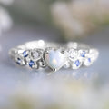 White alloy women's heart ring with floral and ocean pattern design on a hand.