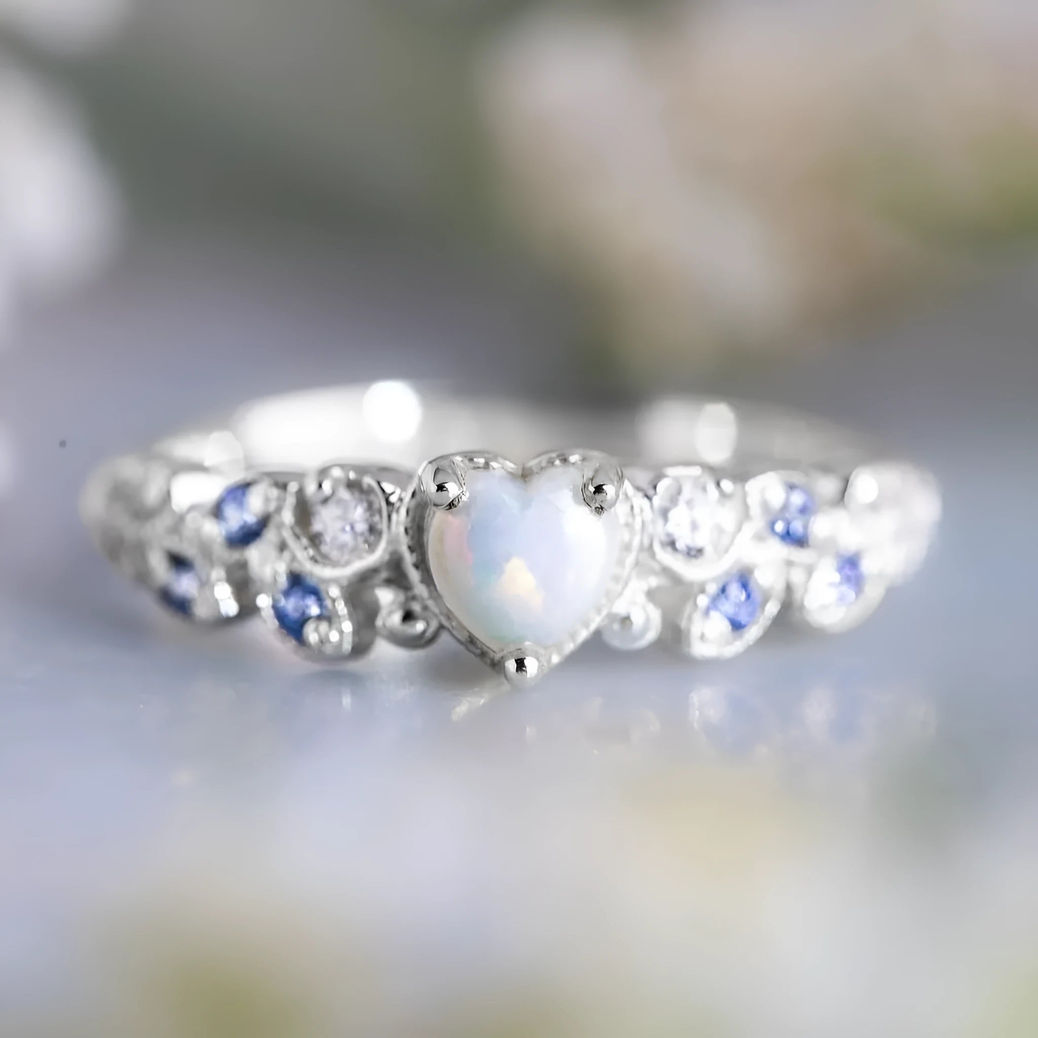 White alloy women's heart ring with floral and ocean pattern design on a hand.