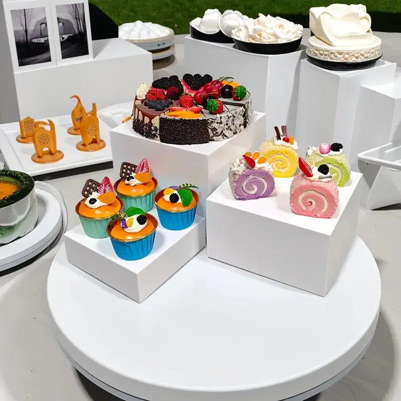 White and transparent plastic cube dessert display stands arranged in a tiered set.