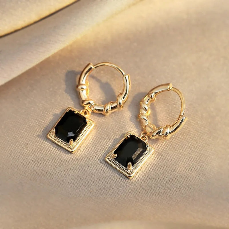 A pair of geometric copper earrings with black zircon stones in a quadrilateral shape.