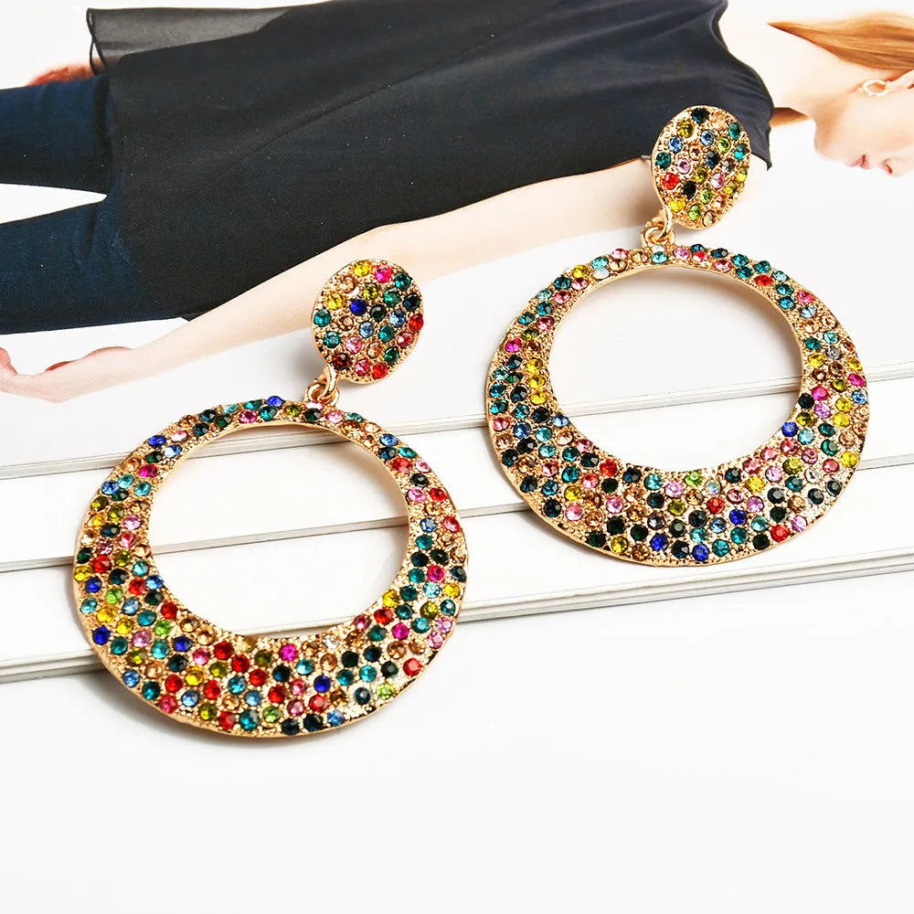 A pair of large round cartoon-style pendant earrings with coloured rhinestones on alloy metal.