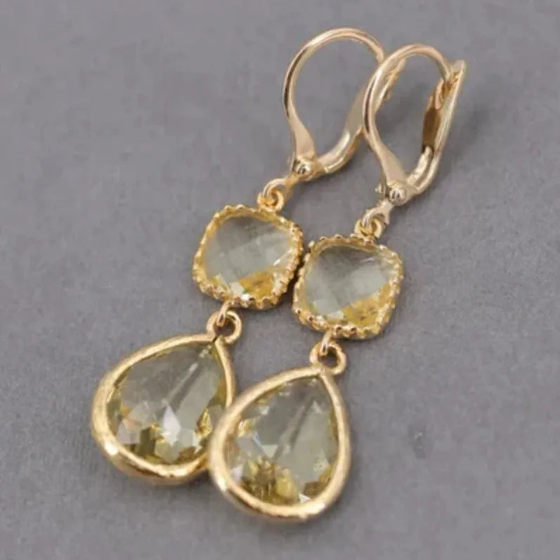 Gold geometric fringe earrings with crystal water droplet details on white background