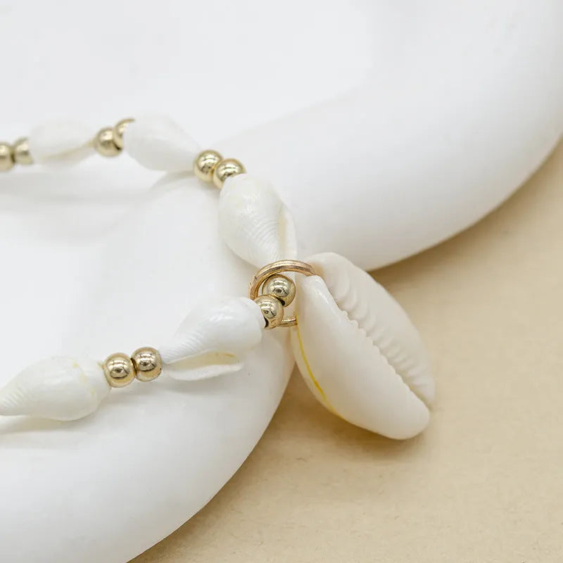 White conch shell bead necklace with a detailed mother pearl shellfish pendant on a regular chain.
