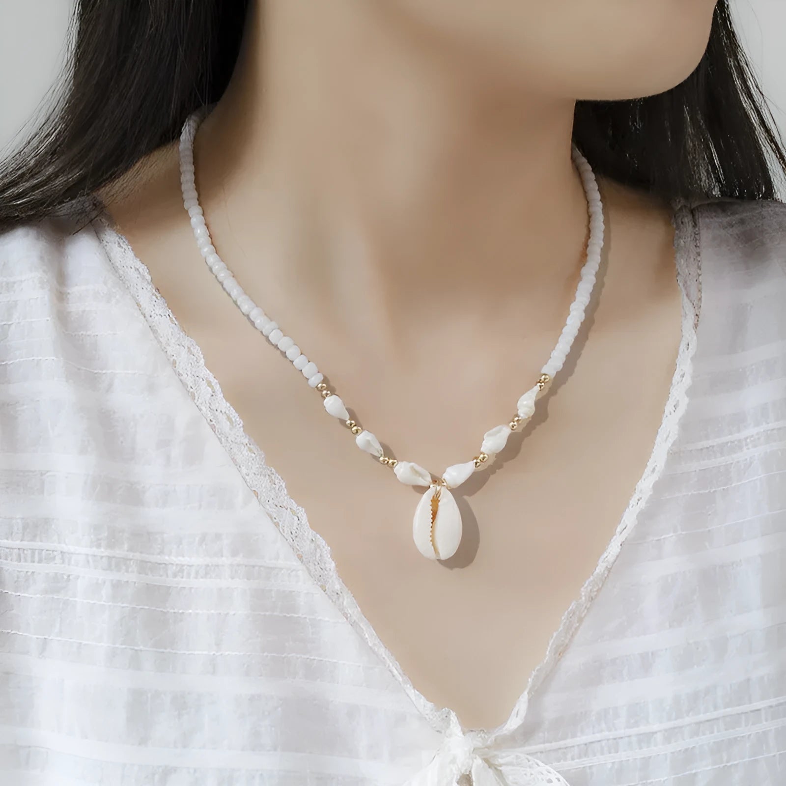 White conch shell bead necklace with a detailed mother pearl shellfish pendant on a regular chain.