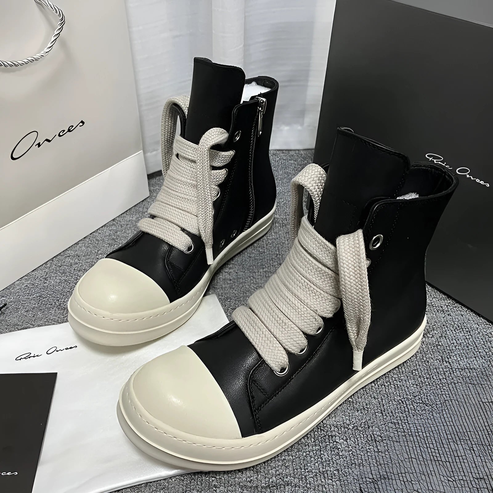 Black high-top leather sneakers with a side zipper and visible stitching on a white background.
