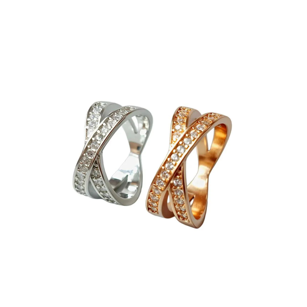 A silver geometric cross ring with micro-inlaid zircon stones on a finger, showing side profile.