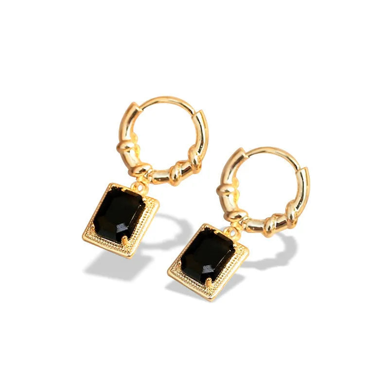A pair of geometric copper earrings with black zircon stones in a quadrilateral shape.