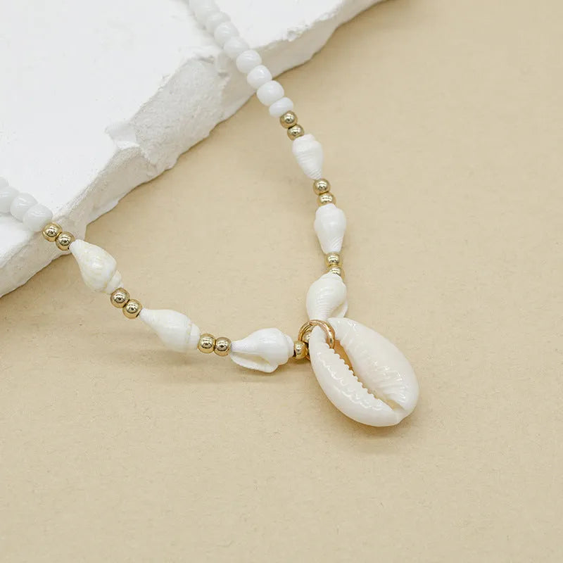 White conch shell bead necklace with a detailed mother pearl shellfish pendant on a regular chain.