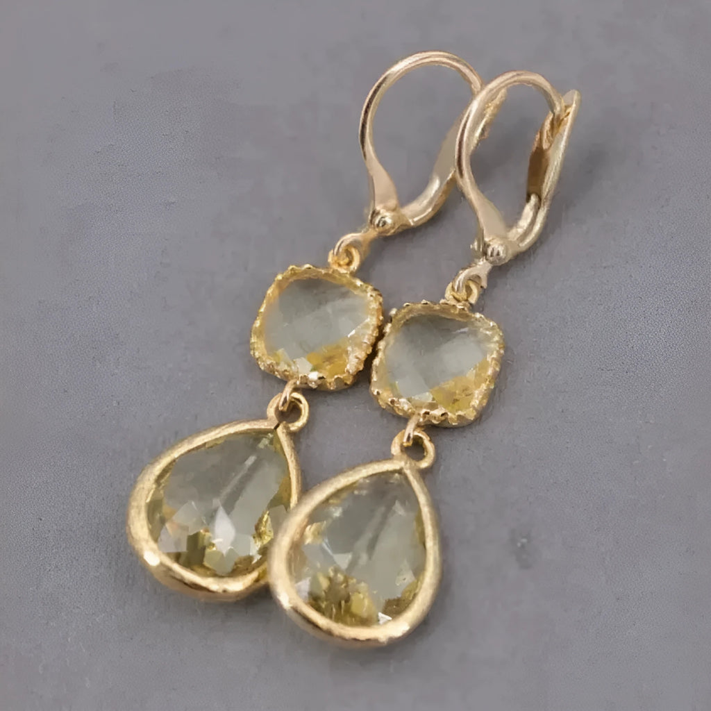 Gold geometric fringe earrings with crystal water droplet details on white background