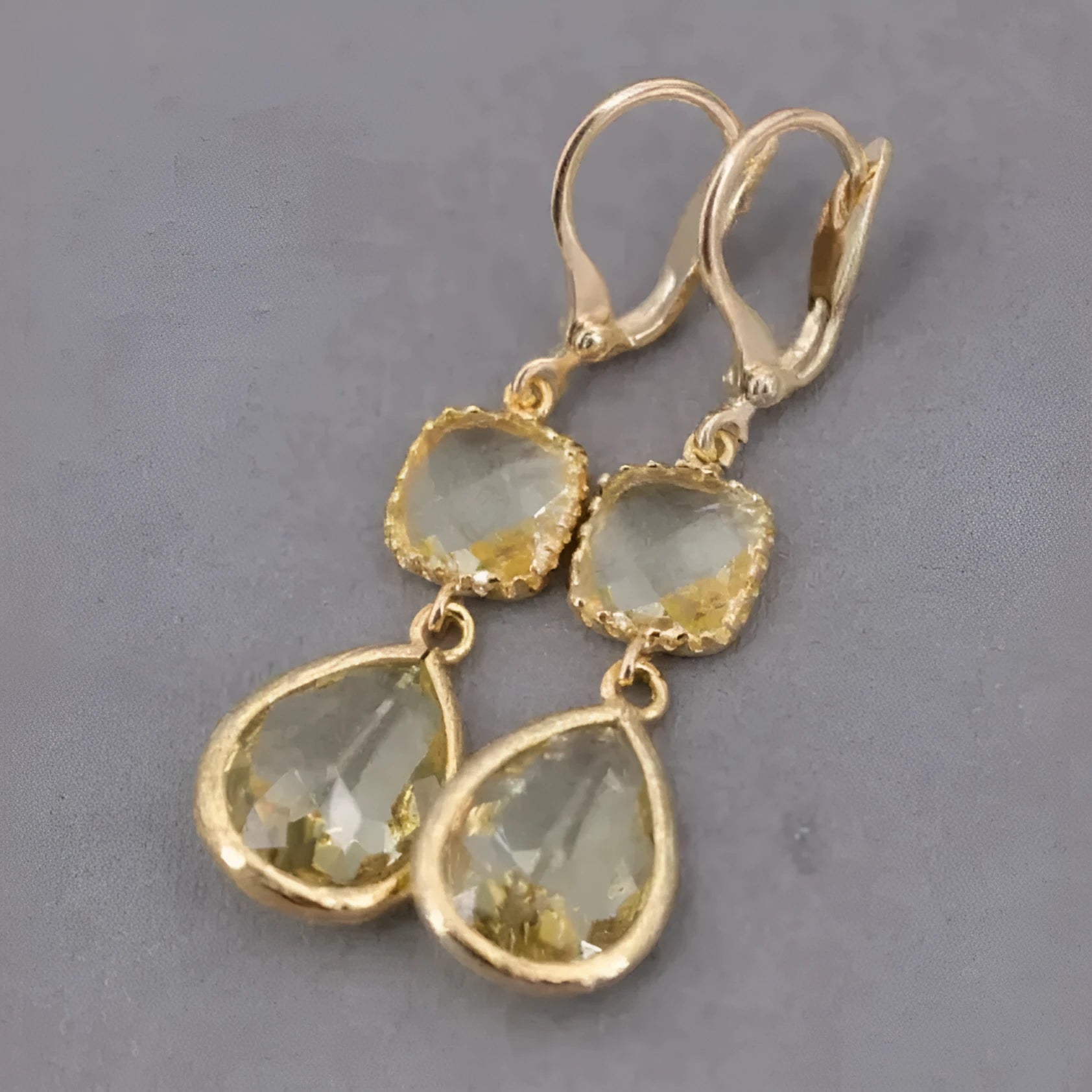 Gold geometric fringe earrings with crystal water droplet details on white background