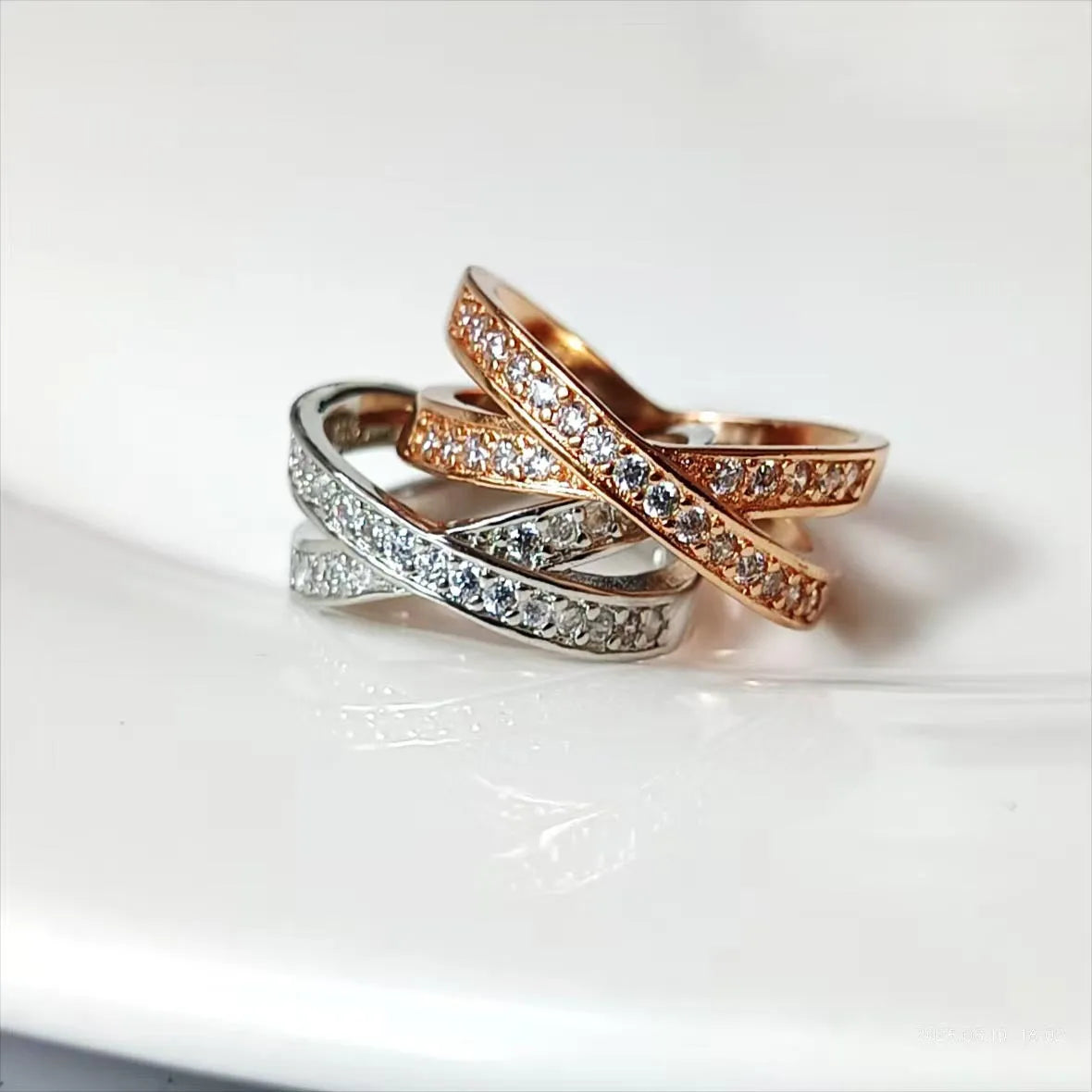 A silver geometric cross ring with micro-inlaid zircon stones on a finger, showing side profile.