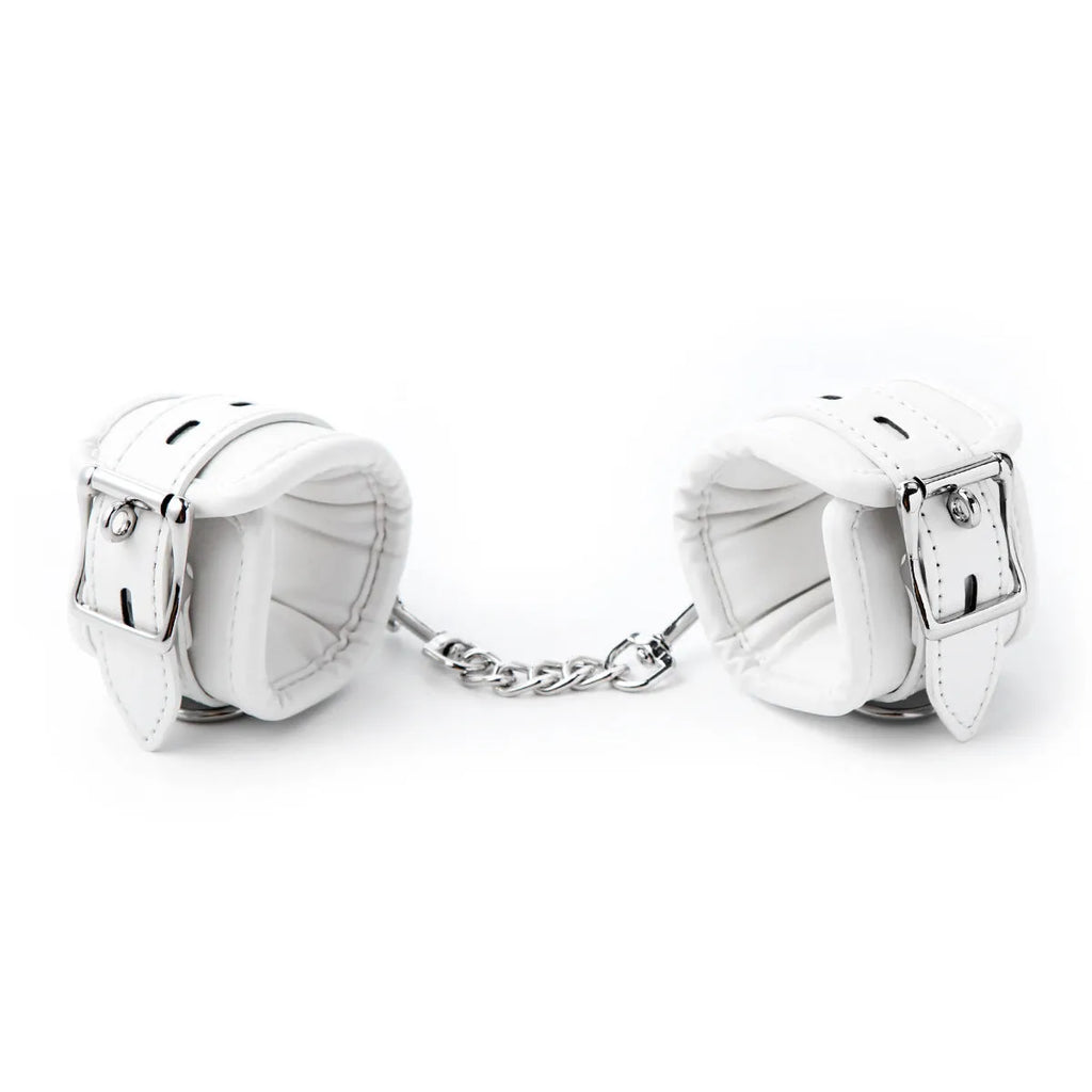 White PU foam bondage set showing handcuffs, ankle cuffs, and a neck scarf on a dark background.