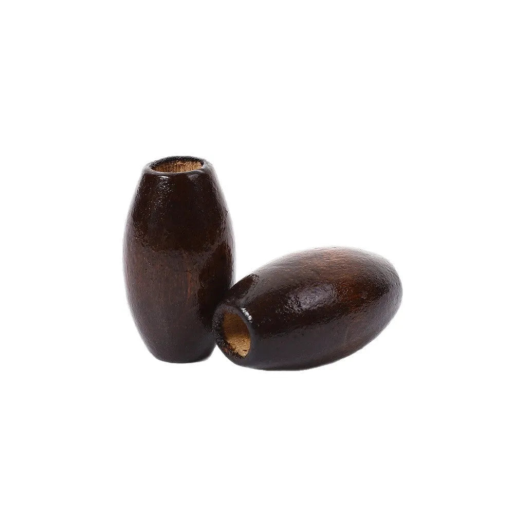 Dark coffee coloured oval wooden bead with a raised M-shaped design, showing scale.