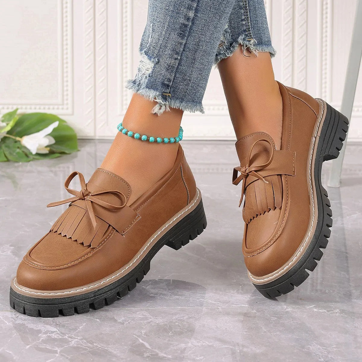 Black women's loafers with a tassel and bow knot on a chunky rubber sole.