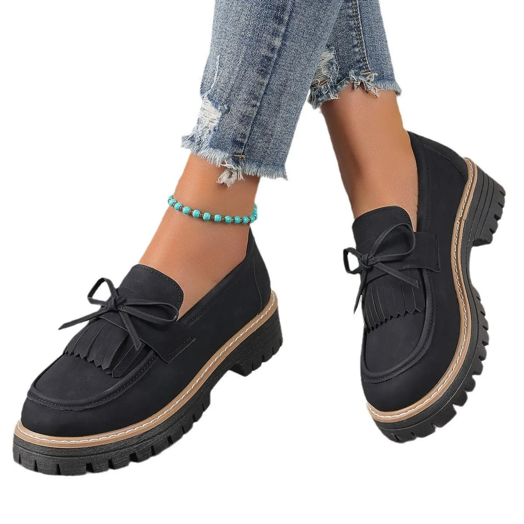 Black women's loafers with a tassel and bow knot on a chunky rubber sole.