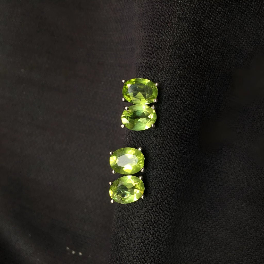 Grass green natural olivine oval stud earrings in sterling silver on a white background.
